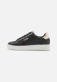 Sneaker nera con motivo del logo in rilievo, accentuato in oro sul tallone, suola bianca e lacci neri. Presenta una tomaia in tessuto liscio.