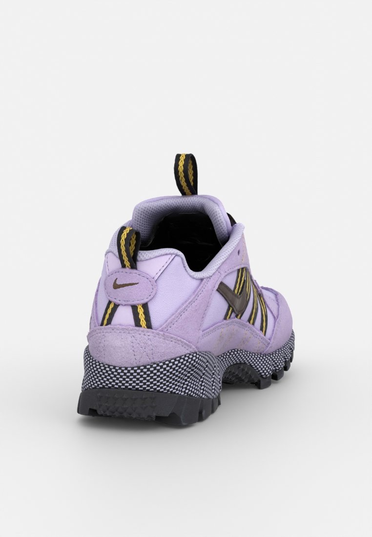 Chaussure de sport violette avec un dessus texturé, des accents noirs et jaunes, une semelle à motifs et une languette au talon.