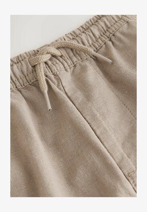 Beige linnedragt med elastisk talje og flettet snørre. Detalje af stoftekstur og syning er synlig.