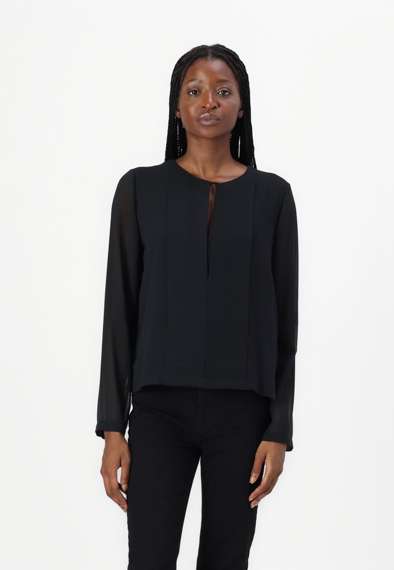 Blusa nera a maniche lunghe con dettaglio a chiave e design plissè. Realizzata in un materiale trasparente, presenta un scollatura tonda e una vestibilità morbida.
