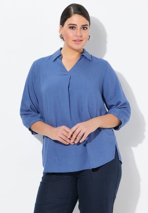 Blusa azul de manga larga con escote en V y detalle de pliegues, con un corte relajado y aberturas laterales, hecha de tela ligera.