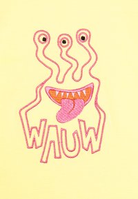 Tela amarilla que presenta un diseño bordado en rosa de un monstruo con tres ojos, dientes afilados, una lengua afuera y la palabra "WAUW."