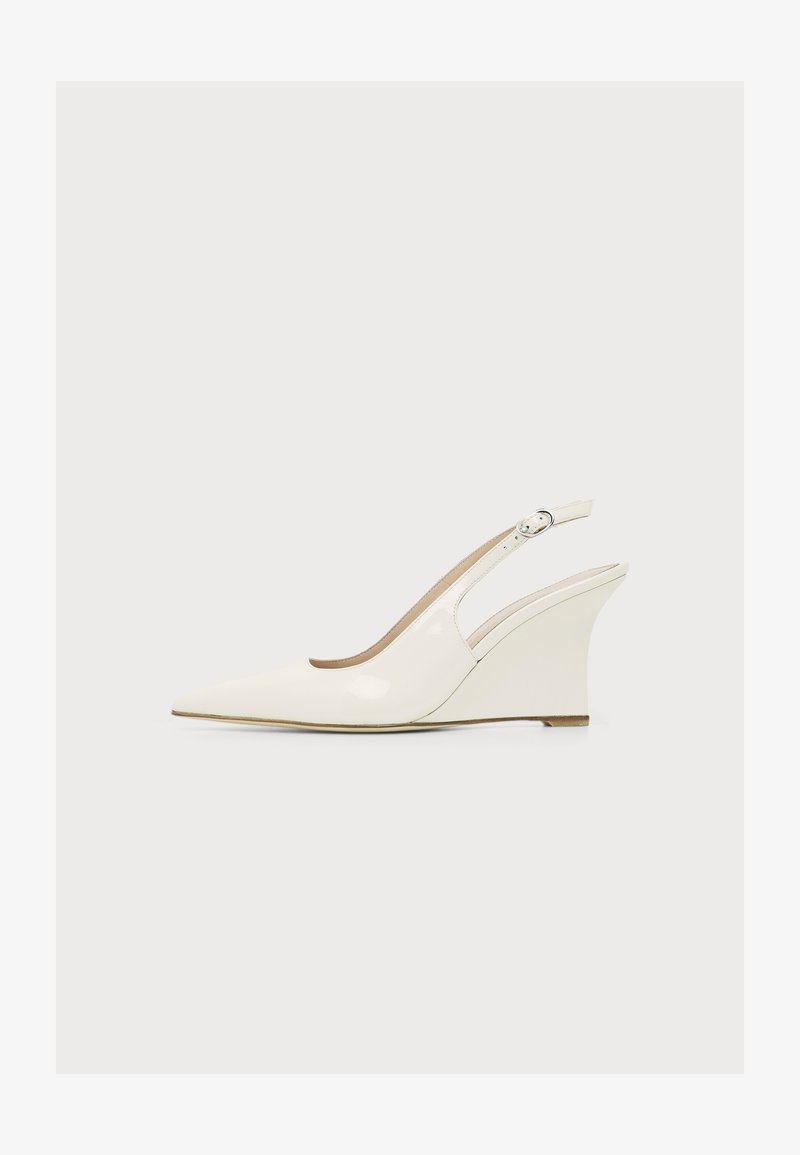 Chaussure compensée à bout pointu couleur crème avec bride arrière réglable à boucle et finition lisse sur fond uni.