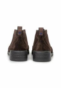 Par de botas de tobillo de ante marrón con suelas gruesas negras, lengüetas traseras con el logotipo azul 'F' y nombre de la marca grabado en las suelas.