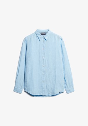 Chemise boutonnée bleu clair fabriquée en tissu doux et texturé, dotée d'un col, de manches longues et d'un ourlet incurvé. Petite étiquette avec logo en bas.