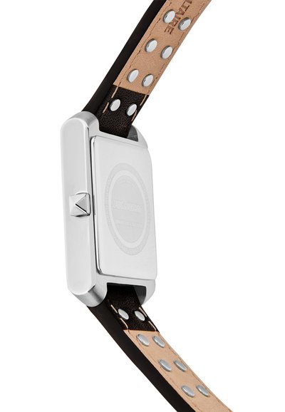 Pravokotna ohišje za uro iz srebra z bočno krono, pritrjeno na dvobarven usnjen pašček s srebrnimi zakovicami in vidnimi šivi.