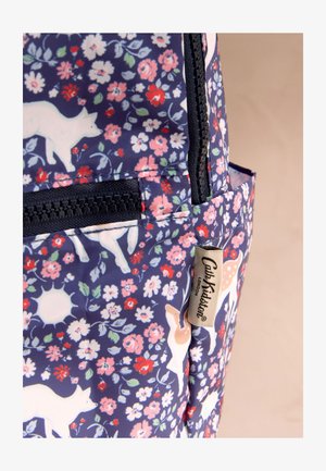 Material pentru rucsac cu siluete albe de câine și cerb, flori roz, roșii și albe pe fundal bleumarin, fermoar și etichetă „Cath Kidston London”.