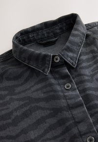 Camicia con bottoni in grigio scuro con un motivo a strisce zebrate sottili, caratterizzata da un colletto tradizionale e bottoni neri. Realizzata in tessuto strutturato.