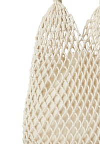 Natural cotton mesh bag, cream color, with an open weave design. Features sturdy straps and a soft, unstructured bottom.