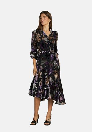 Vestido envolvente negro con estampado floral y un dobladillo con volantes, que presenta detalles en púrpura y dorado, mangas largas y un cinturón atado en la cintura. Textura suave.