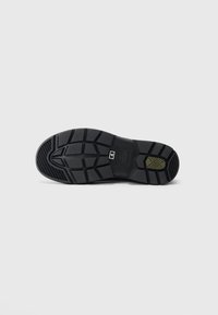 Zwarte shoesole met diepe profielpatronen, een maat 4 label, en een klein olijfgroen textuurgebied nabij de hiel.