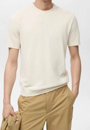 Kortærmet rundhalset sweater i off-white struktureret strik; kombineret med khakibukser; uden synlige mønstre eller metaldekorationer.