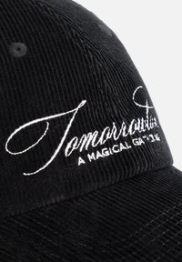 Zwarte corduroy pet met witte geborduurde tekst "Tomorrow" en een slogan. Textiel met een gestructureerde stof en verticale ribbels, voorzien van een verstelbare sluiting.