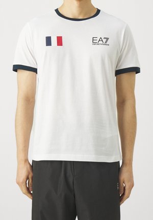 White cotton t-shirt with navy crew neck and sleeve trim, featuring a small French flag and EA7 logo on the chest.
