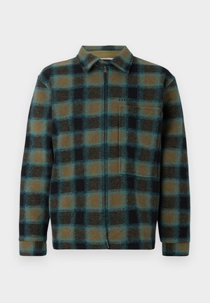 Camicia in flanella a quadri nei colori marrone, nero e teal; presenta una zip completa, colletto e un piccolo logo sul petto; texture morbida, maniche lunghe.