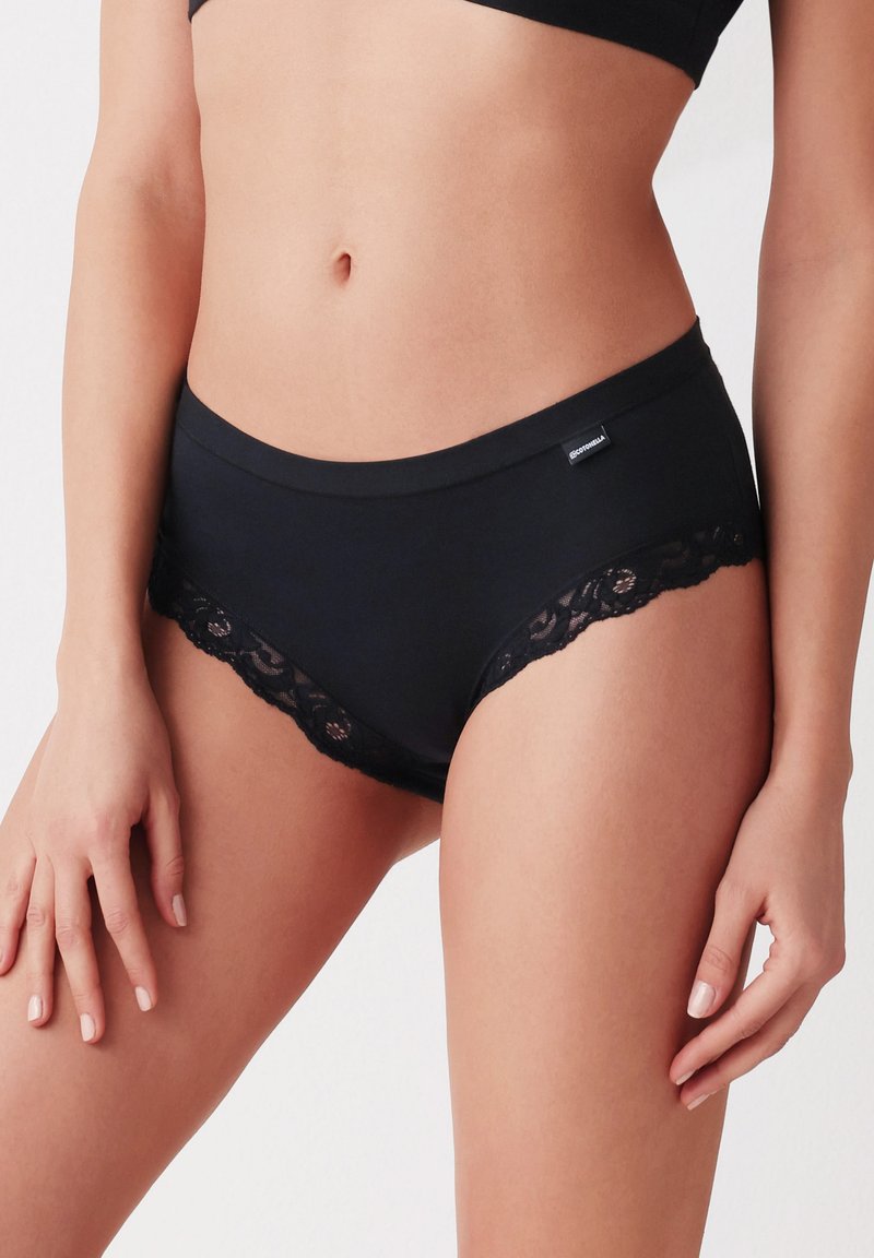Zwarte hipsteronderbroek van zacht materiaal, met een geschulpte kantafwerking langs de benen en een klein label op de tailleband.