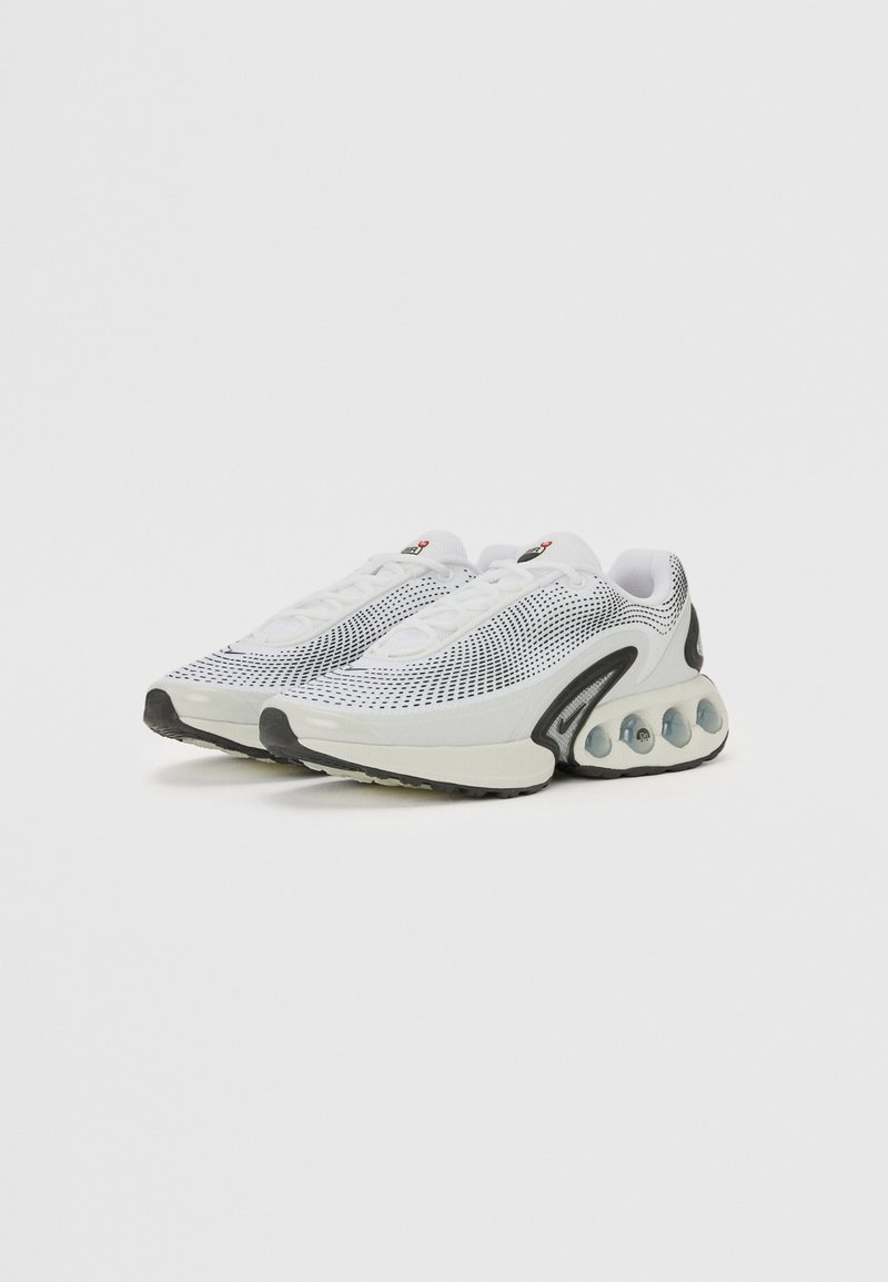 Baskets de sport blanches avec une tige en mesh et des accents noirs, une semelle rembourrée avec des sections transparentes et un laçage.