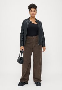 Black faux leather jacket, black ribbed top, brown corduroy wide-leg pants, structured black handbag, chunky black shoes.