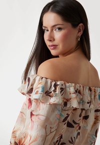 Floral off-the-shoulder blouse featuring a ruffled neckline, in soft beige with pink, blue, and brown flower patterns. Smooth texture, lightweight fabric.