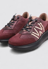 Baskets de sport bordeaux avec des matériaux texturés, un design élégant, des lacets noirs et un logo de couleur contrastante bien en vue sur le côté.