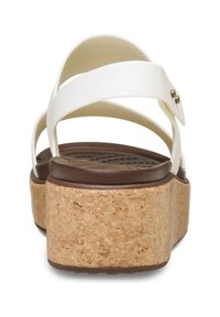 Sandalias de cuña blancas con plataforma de corcho. Cuentan con tiras cruzadas y un acento metálico. Plantilla de color marrón texturada para mayor agarre y comodidad.
