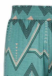 Turquoise fabric with a textured elastic waistband; features black and peach geometric patterns including chevrons and triangles.