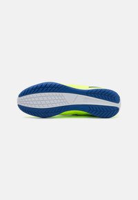 Suela de zapato deportivo con una parte superior amarillo-verde vibrante, una parte inferior de goma azul texturizada y una entresuela blanca con un patrón de banda diagonal.