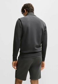 Mörkgrå sweatshirt med hög krage och ribbade muddar, ihop med matchande shorts. Slät textur, minimalistisk design, inga synliga mönster eller detaljer.