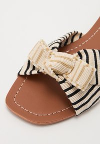 Stripete slide sandal med en sløyfebrysten, laget av vevet stoff i beige og svart, med en brun syntetisk såle og synlig sømdetalj.