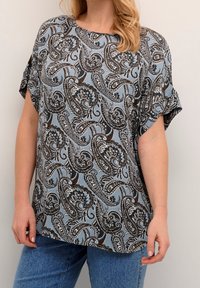 Blusa de color azul claro con un patrón de paisley en blanco y negro. Mangas cortas y un corte holgado, fabricada con una tela suave y texturizada.