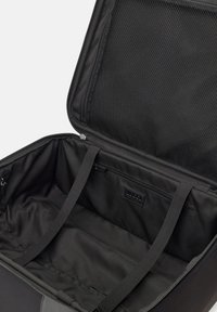 Czarna torba podróżna o przestronnym wnętrzu, wykonana z gładkiego materiału, z siateczkowymi kieszeniami, dwoma paskami i zamkiem błyskawicznym.