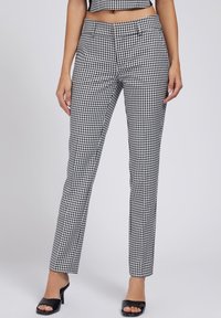 Svartvita ginghamrutiga byxor med smal passform, tyget är slätt, med slät framdel och sidofickor. Bärs med svarta klackskor.