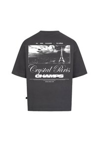 Šedé tričko s krátkým rukávem a oversize střihem. Na zádech je grafika černobílé Eiffelovy věže a text: "Crystal Paris CHAMPS".