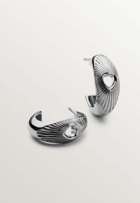 Pendientes de aro plateados con un diseño estriado y recortes en forma de corazón. Superficie lisa y brillante con propiedades reflectantes.