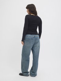 Black long-sleeve fitted top with a round neckline and a back cut-out, paired with loose blue denim jeans featuring large back pockets.