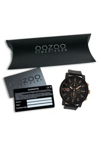 Montre analogique noire avec des accents dorés, trois sous-cadrans et un bracelet en cuir texturé. Comprend l'emballage, la carte de garantie et le livret de garantie.