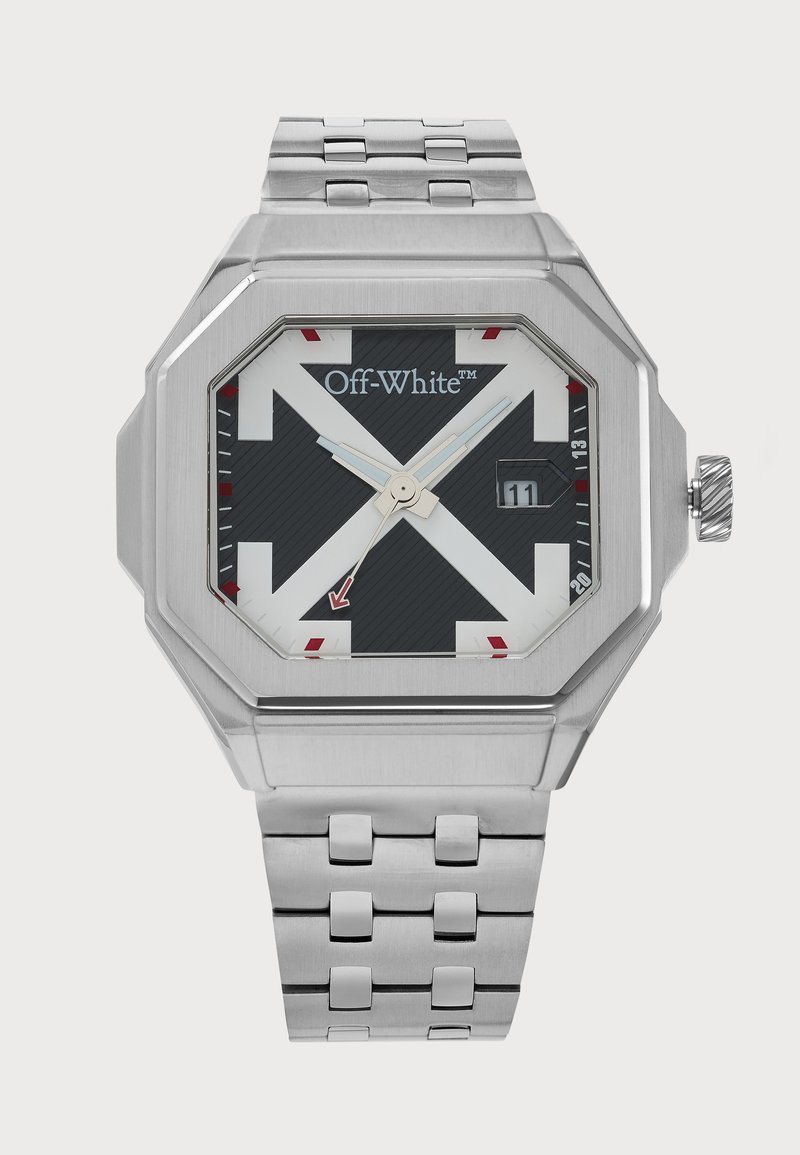 Montre-bracelet argentée blanc cassé, avec bracelet à maillons en métal, boîtier octogonal, cadran noir et blanc, touches de rouge et affichage de la date indiquant 11.