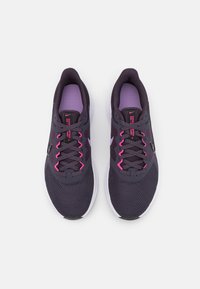 Baskets de course en maille violette avec des accents noirs et roses. Les caractéristiques incluent un tissu texturé, des lacets brillants et une semelle blanche.
