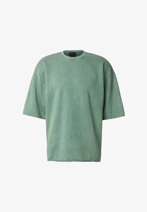 Nagyméretű zöldes rövid ujjú póló, puha pamutanyagból készült. Kerek nyakkivágással és nyers szegélyekkel rendelkezik.