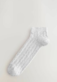 Witte gebreide sok met een textuurpatroon, geribbelde bovenkant, versterkte hiel en teen. Smalle afwerking en naadloos ontwerp.