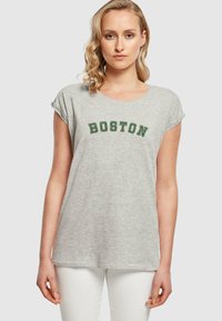 Hall kombinesega lühikeste varrukatega hall T-särk, mille ees on tumeroheline tikandiga sõna "BOSTON". Pehme kudum, mis on mugava lõikega.