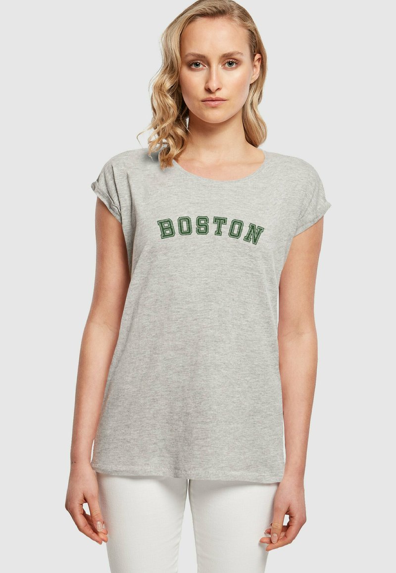 Hall kombinesega lühikeste varrukatega hall T-särk, mille ees on tumeroheline tikandiga sõna "BOSTON". Pehme kudum, mis on mugava lõikega.