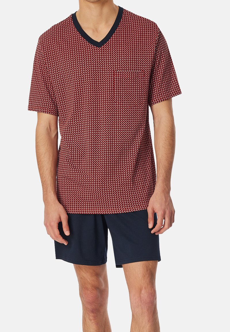 Rot und marinefarbenes kurzärmeliges V-Ausschnitt-T-Shirt mit geometrischem Muster, ausgestattet mit einer Brusttasche und kombiniert mit marinefarbenen Shorts. Weicher Stoff.