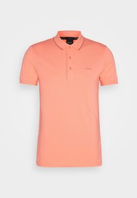 Polo corail en coton, avec une patte de boutonnage à deux boutons, des manches courtes, et un marquage discret sur la poitrine et le bord du col.