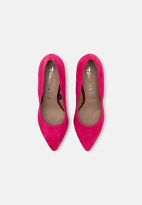 Paire de ballerines pointues pour femmes en daim rose vif avec semelles intérieures beiges sur un fond clair uni.