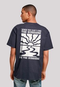 Navy cotton T-shirt with short sleeves featuring a graphic design of sun rays and a river on the back, with white text above and below.