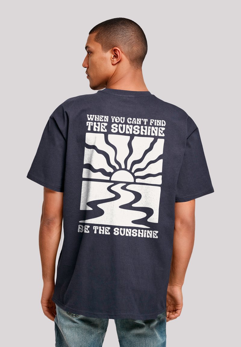 Navy cotton T-shirt with short sleeves featuring a graphic design of sun rays and a river on the back, with white text above and below.