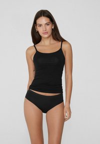 Schwarzes nahtloses Oberteil mit dünnen Trägern, kombiniert mit passenden hochgeschnittenen Bikiniunterhosen, beide aus einem glatten, dehnbaren Stoff.