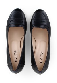 Scarpe flat in pelle nera con punta arrotondata, caratterizzate da un accento decorativo a forma di fiocco e un interno beige. Il marchio "EVITA" è visibile all'interno.