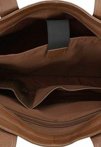 Interno di una borsa a tracolla in pelle marrone che mostra molteplici scomparti, una cintura elastica nera e una tasca con zip con una fodera in tessuto marrone chiaro.
